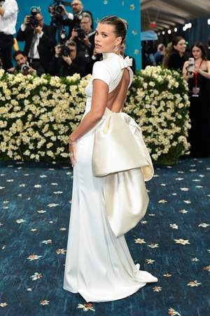 Sofia Richie Grainge in custom Tommy Hilfiger white gown with large bow on the back, looking back at the camera for Met Gala 2025
